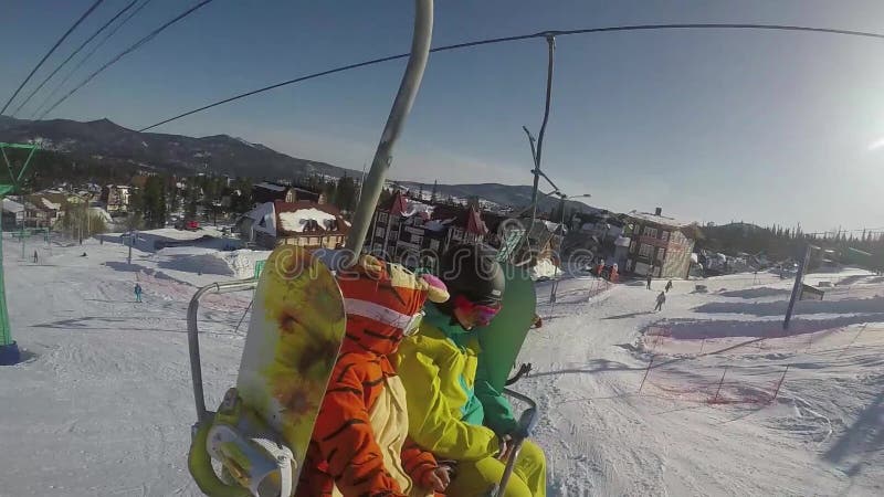 2 смешных пары snowboarders ехать вверх по подъему лыжи в солнечный зимний день 1920x1080 видеоматериал