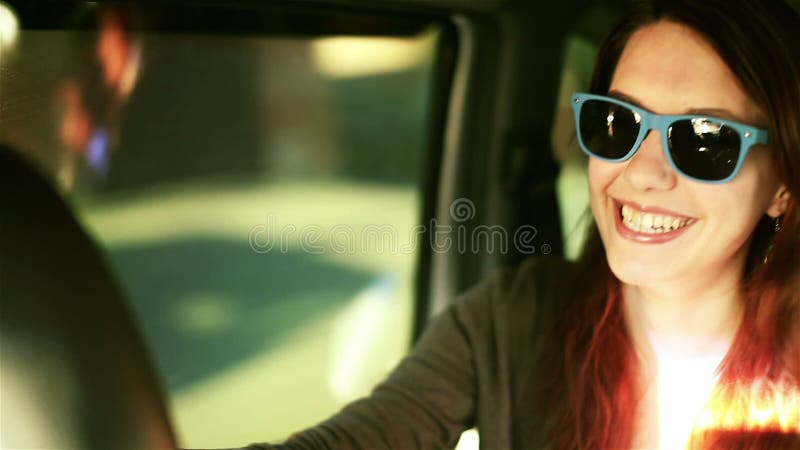 Смеясь над женщина в солнечных очках внутри утехи автомобиля едет