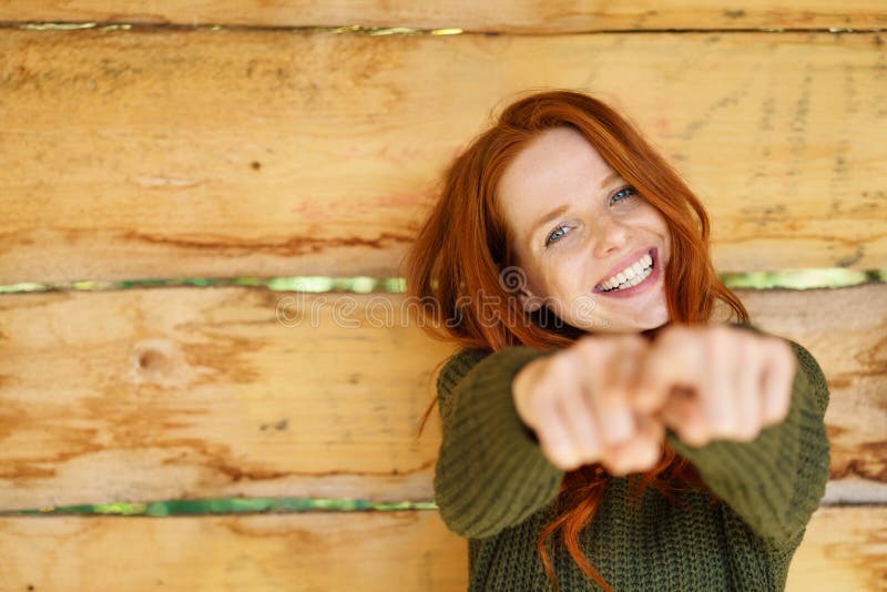 Смеясь над vivacious redhead указывая на камеру стоковое изображение