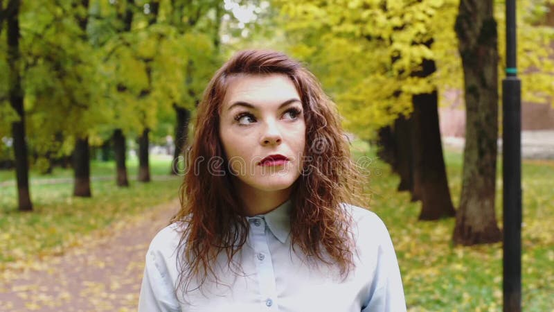 Смущенная молодая женщина redhead в парке видеоматериал