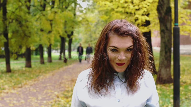 Смущенная молодая женщина redhead в парке сток-видео