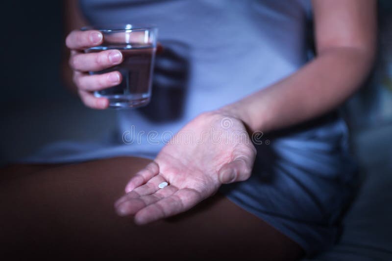 Снотворное в руке Женщина сидя на кровати с медициной для инсомнии или melatonin стоковая фотография rf Снотворное в руке Женщина сидя на кровати с медициной для инсомнии или melatonin стоковая фотография rf
