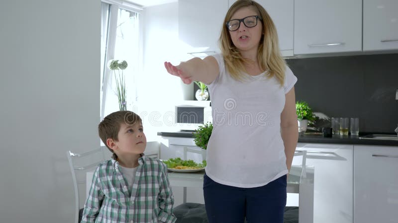 Современные танцы, мать в стеклах учат движениям танца сына дома в кухне