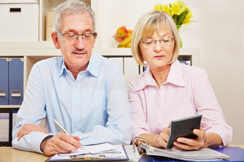 Couple of seniors together makes the tax declaration at the desk. Couple of seniors together makes the tax declaration at the desk