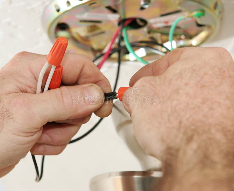 A closeup of an electrician's hands as he connects wires using a wire-nut. All work is being performed to code by a licensed master electrician. A closeup of an electrician's hands as he connects wires using a wire-nut. All work is being performed to code by a licensed master electrician.