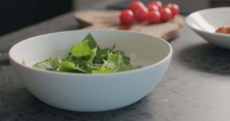 Создание салата из кесаря с курицей и вишневыми томатами в белой миске стоковые изображения