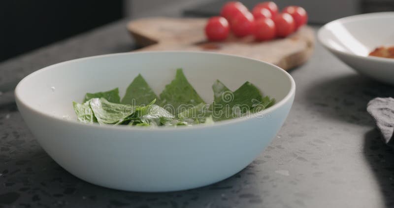 Создание салата из кесаря с курицей и вишневыми томатами в белой миске стоковые фото
