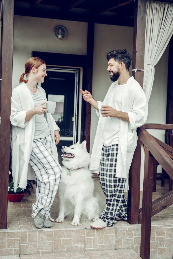Соперничанные пары наслаждаясь кофе утра пока samoyed сидя рядом с стоковые фото Соперничанные пары наслаждаясь кофе утра пока samoyed сидя рядом с стоковые фото