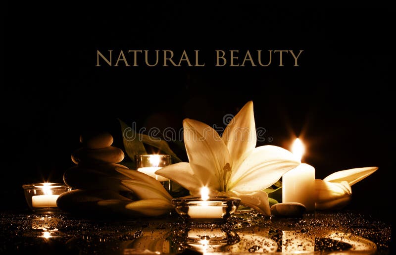 Beauty composition with white lily, burning candles and stack of stones in gold and black colors. Beauty composition with white lily, burning candles and stack of stones in gold and black colors