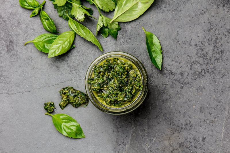 Соус Chimichurri Аргентина зеленеет chimichurri соуса базилика петрушки для asado барбекю в стеклянном опарнике, сером шифере стоковые изображения Соус Chimichurri Аргентина зеленеет chimichurri соуса базилика петрушки для asado барбекю в стеклянном опарнике, сером шифере стоковые изображения