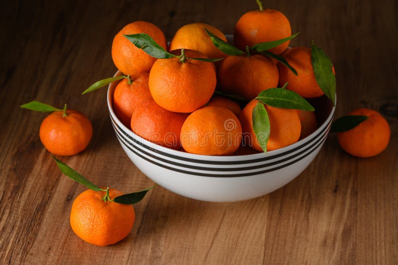 fresh juicy tangerines in a white bowl on a wooden table 1. fresh juicy tangerines in a white bowl on a wooden table 1