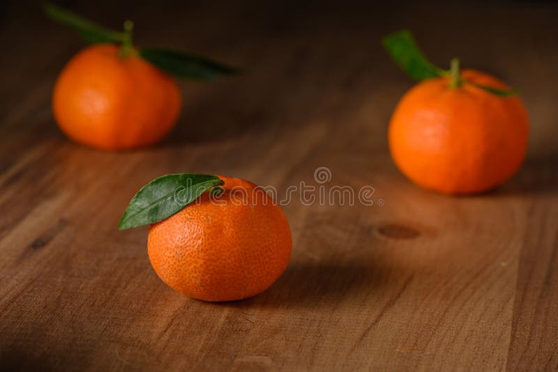 fresh juicy three tangerines on a wooden table 2. fresh juicy three tangerines on a wooden table 2
