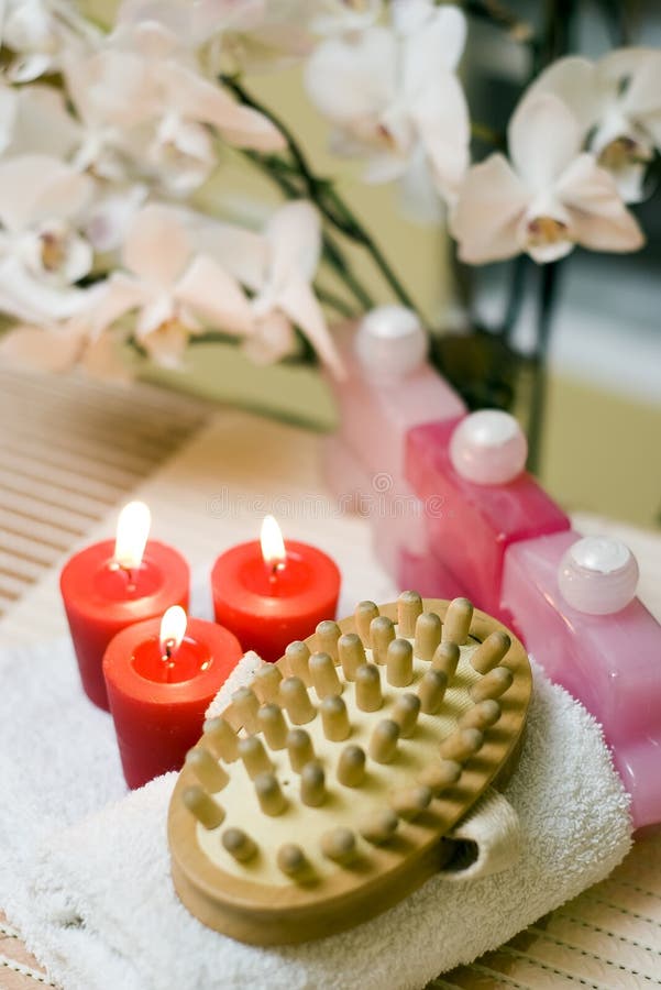 A spa massage brush composition with red items and orchid flower in the background. A spa massage brush composition with red items and orchid flower in the background.