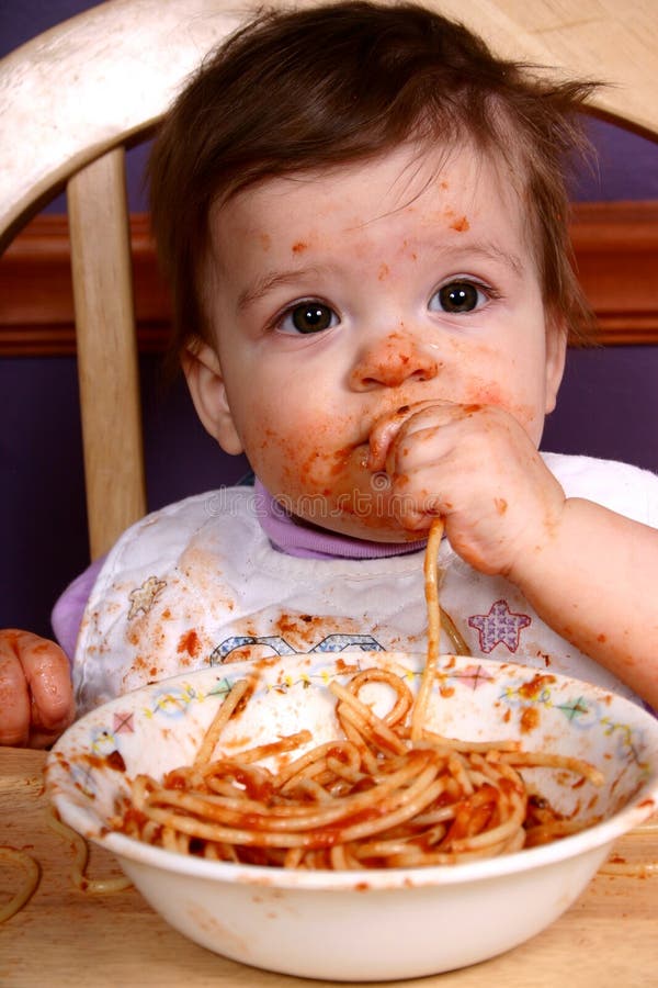 Adorable baby sitting in high chair eating a bowl of spaghetti. Adorable baby sitting in high chair eating a bowl of spaghetti.