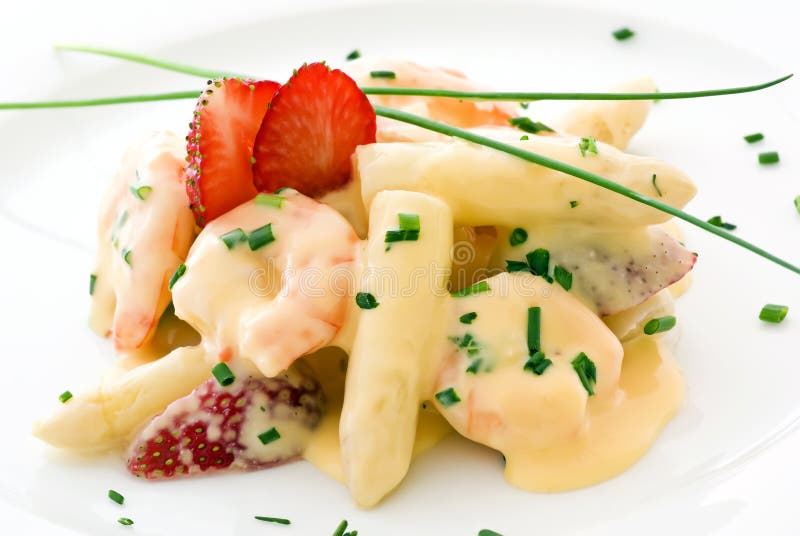 Asparagus with prawns and strawberries as closeup on a white dish. Asparagus with prawns and strawberries as closeup on a white dish