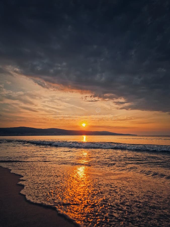 Calm morning seaside with beautiful sunrise at horizon and foamy waves hits the sandy beach. Calm morning seaside with beautiful sunrise at horizon and foamy waves hits the sandy beach.