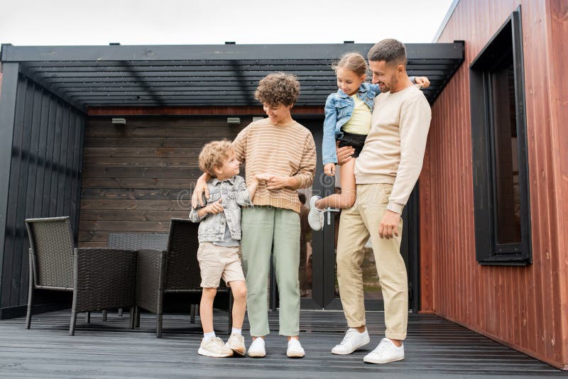 Спокойные семья молодых родителей и их 2 прелестных маленьких детей в casualwear стоковая фотография rf