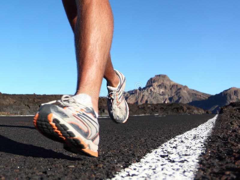 Running sport shoes closeup outdoors in action on mountain road. Male shoes on young man training in beautiful landscape. Slight motion blur, focus on back running shoe. Running sport shoes closeup outdoors in action on mountain road. Male shoes on young man training in beautiful landscape. Slight motion blur, focus on back running shoe.