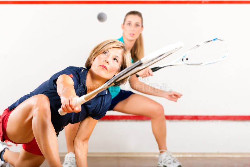 Two women playing squash as racket sport in gym, it might be a competition. Two women playing squash as racket sport in gym, it might be a competition