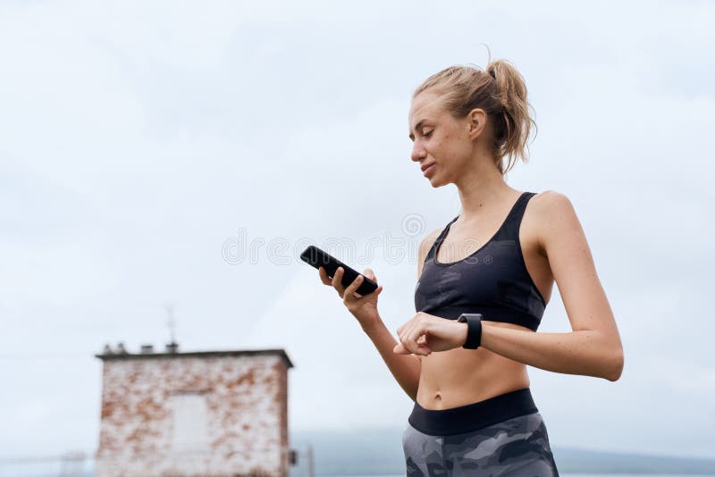 спортсменка устанавливает смартфон и следит за тренировкой стоковая фотография