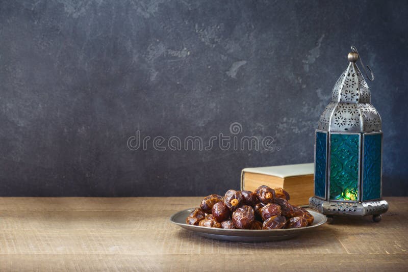 Lightened lantern and dates fruit on wooden table over dark background. Ramadan Kareem holiday celebration concept. Lightened lantern and dates fruit on wooden table over dark background. Ramadan Kareem holiday celebration concept