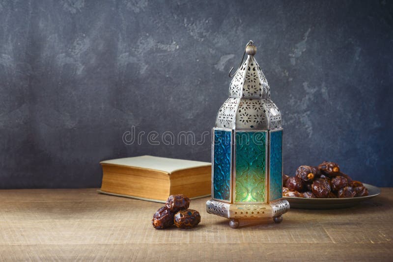 Lightened lantern and dates fruit on wooden table over dark background. Ramadan Kareem holiday celebration concept. Lightened lantern and dates fruit on wooden table over dark background. Ramadan Kareem holiday celebration concept