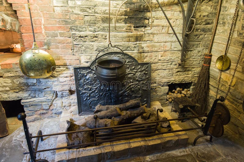 Ancient fireplace with old metal pot hanging over coals. Medieval house interior. Ancient fireplace with old metal pot hanging over coals. Medieval house interior.