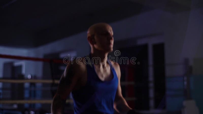 средний кадр спортивного лысого боксера, который тренируется с пропуском верёвки перед боксерской тренировкой в спортивном клубе