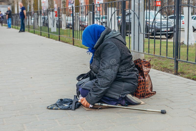Старая бездомная женщина сидит на улице и умоляет деньгам стоковые фото Старая бездомная женщина сидит на улице и умоляет деньгам стоковые фото