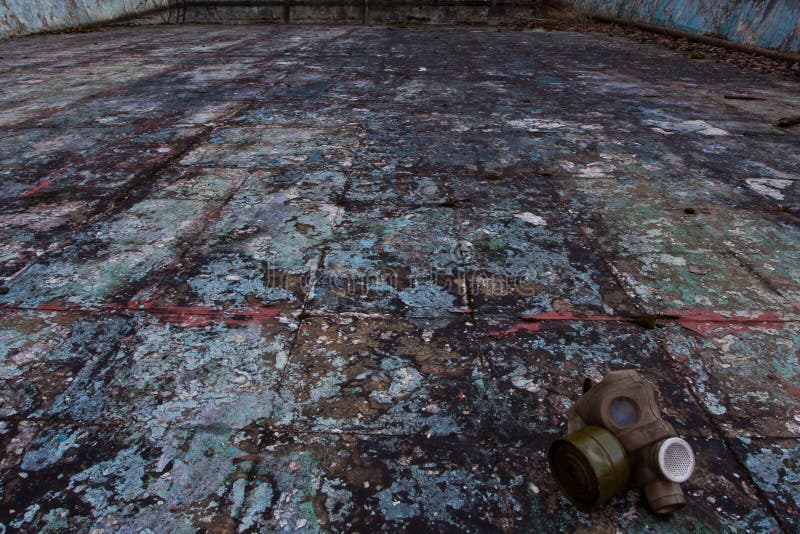 The old gas mask lies on a destroyed concrete floor, a symbol of the horrors of nuclear war and chemical weapons and doom. The old gas mask lies on a destroyed concrete floor, a symbol of the horrors of nuclear war and chemical weapons and doom