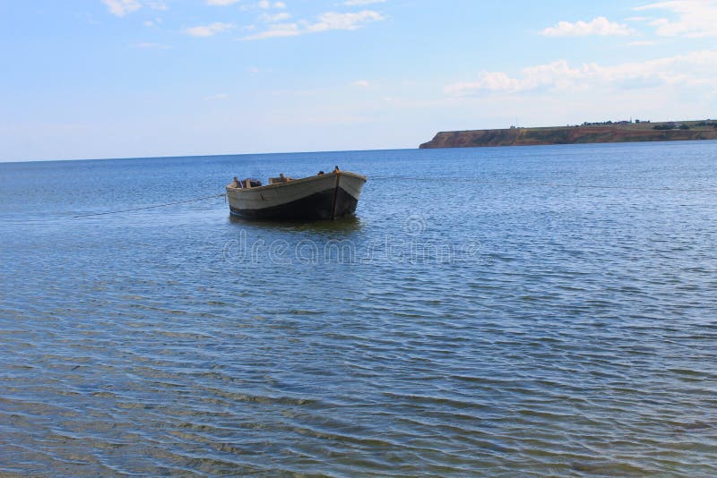 Старая рыбацкая лодка на анкере в море около берега песка стоковые изображения Старая рыбацкая лодка на анкере в море около берега песка стоковые изображения