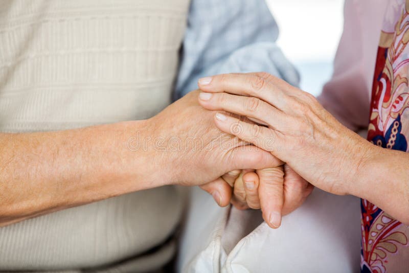 Cropped image of senior couple holding hands while sitting on chairs at nursing home. Cropped image of senior couple holding hands while sitting on chairs at nursing home