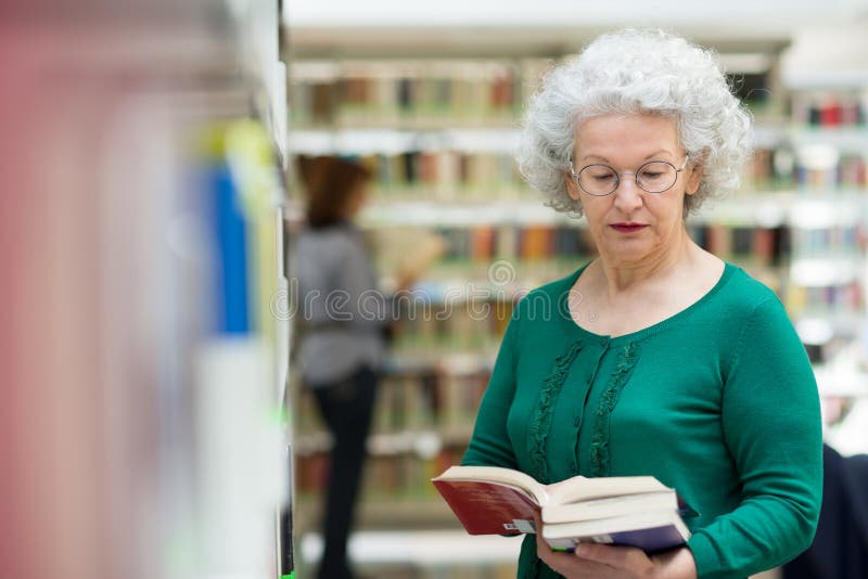 Старшие чтение женщины и книга выбирать в архиве стоковые изображения rf Старшие чтение женщины и книга выбирать в архиве стоковые изображения rf