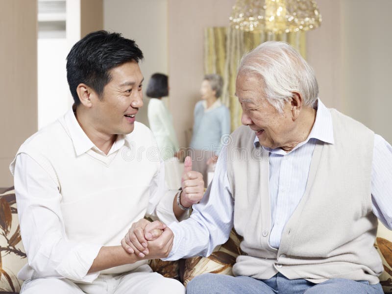 Senior asian father and adult son chatting on couch. Senior asian father and adult son chatting on couch