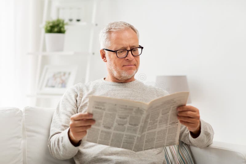 Leisure, information, people and mass media concept - senior man in glasses reading newspaper at home. Leisure, information, people and mass media concept - senior man in glasses reading newspaper at home