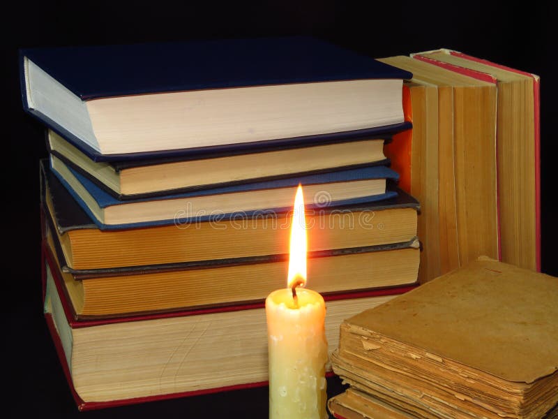Старые книги штабелированные в куче и горящей свече стоковые изображения rf Старые книги штабелированные в куче и горящей свече стоковые изображения rf