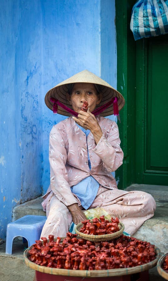 Старый поставщик продавая гончарню забавляется на улице в Hoi, Вьетнаме