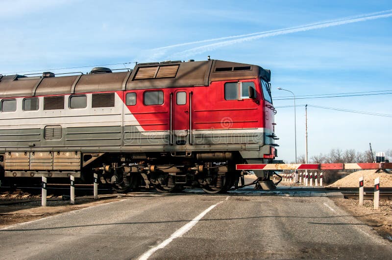 Старый русский красный поезд проходя через ровное скрещивание, на малой дороге стоковая фотография Старый русский красный поезд проходя через ровное скрещивание, на малой дороге стоковая фотография