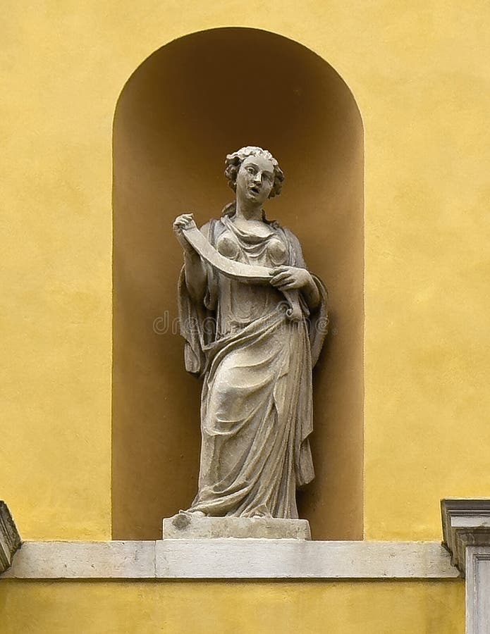 Pictured is a statue of the Muse of Eloquence, Calliope, with a roll of paper on the exterior of the Teatro Communale Alighieri, an opera house located at 2 Via Miriani in Ravenna, Italy. The theatre was designed by Venetian architects, Tommaso Meduna and his brother Giambattista and was inaugurated on the 15th of May 1852. It was named for the famous poet, Dante Aligheri who spent the last four years of his life in Ravenna. Reflecting the style of the Venetian brothers, the exterior of the Alighieri is neo-classical with a four ionic columns and a portico with statues of four Muses. Pictured is a statue of the Muse of Eloquence, Calliope, with a roll of paper on the exterior of the Teatro Communale Alighieri, an opera house located at 2 Via Miriani in Ravenna, Italy. The theatre was designed by Venetian architects, Tommaso Meduna and his brother Giambattista and was inaugurated on the 15th of May 1852. It was named for the famous poet, Dante Aligheri who spent the last four years of his life in Ravenna. Reflecting the style of the Venetian brothers, the exterior of the Alighieri is neo-classical with a four ionic columns and a portico with statues of four Muses.
