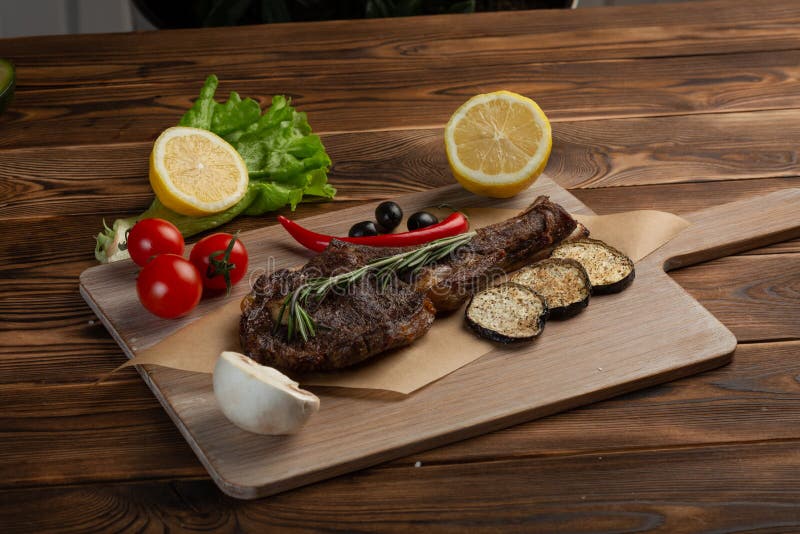 Стейк овечки с овощами и томатным соусом на деревянной предпосылке стоковая фотография Стейк овечки с овощами и томатным соусом на деревянной предпосылке стоковая фотография