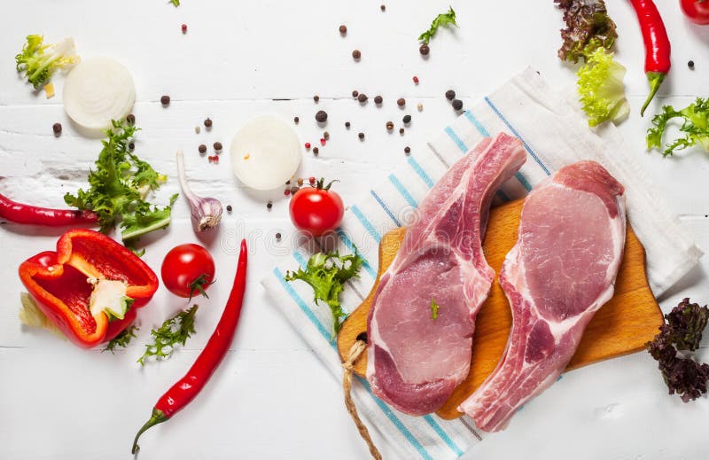 Стейк свинины 2 с мясом и свежими специями приправой на белой деревянной предпосылке, взгляд сверху стоковое фото Стейк свинины 2 с мясом и свежими специями приправой на белой деревянной предпосылке, взгляд сверху стоковое фото