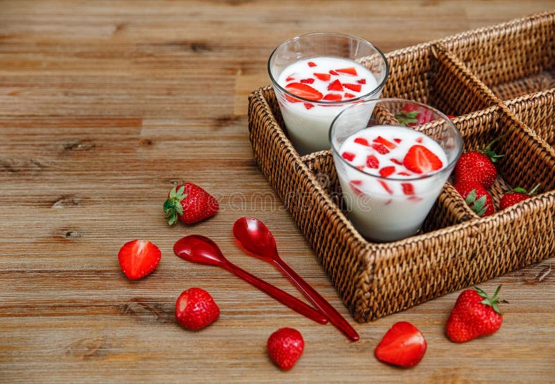 2 стекла югурта, красные свежие клубники в коробке ротанга с пластичными ложками на деревянном столе Завтрак органический здоровы стоковые изображения 2 стекла югурта, красные свежие клубники в коробке ротанга с пластичными ложками на деревянном столе Завтрак органический здоровы стоковые изображения