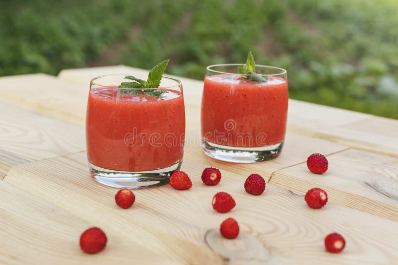 Стекло smoothie клубники на деревянном столе с мятой стоковые фотографии rf Стекло smoothie клубники на деревянном столе с мятой стоковые фотографии rf