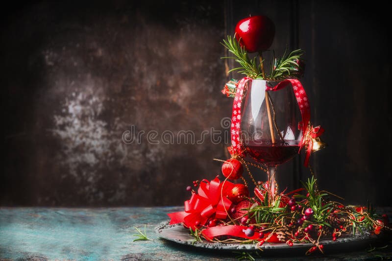 Glass of red wine on rustic table with festive Christmas decoration and rosemary at dark wooden background, side view, place for text. Glass of red wine on rustic table with festive Christmas decoration and rosemary at dark wooden background, side view, place for text