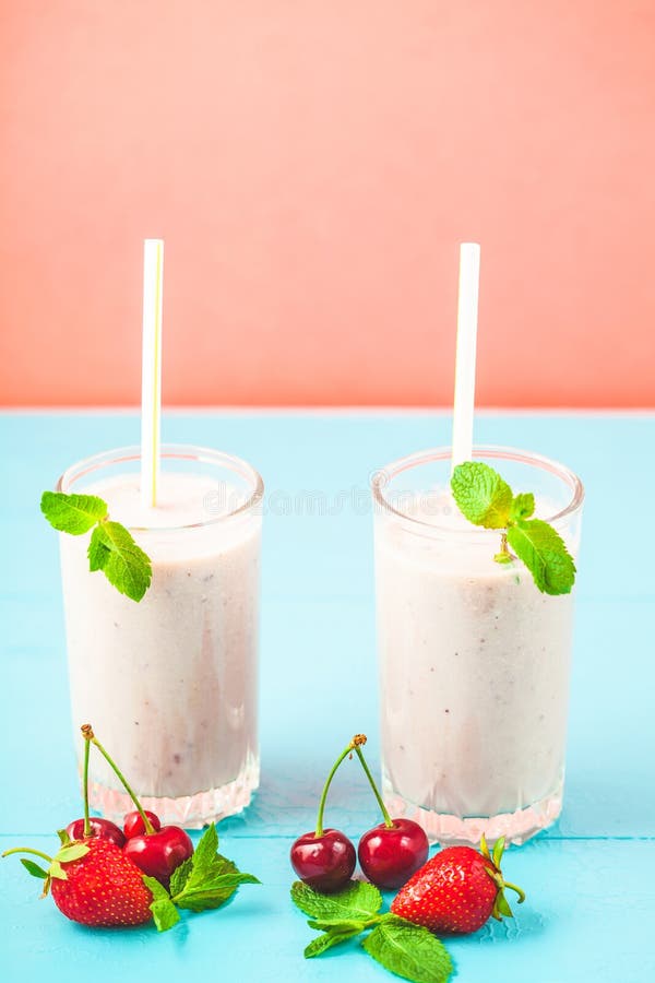 2 стекла smoothies от молока, клубник, бананов, вишен, украшенных с мятой на яркой розовой сини стоковые изображения 2 стекла smoothies от молока, клубник, бананов, вишен, украшенных с мятой на яркой розовой сини стоковые изображения