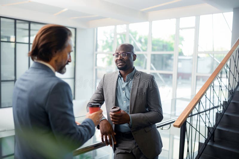 Стекла бородатого темнокожего человека нося говоря с коллегой стоковое фото