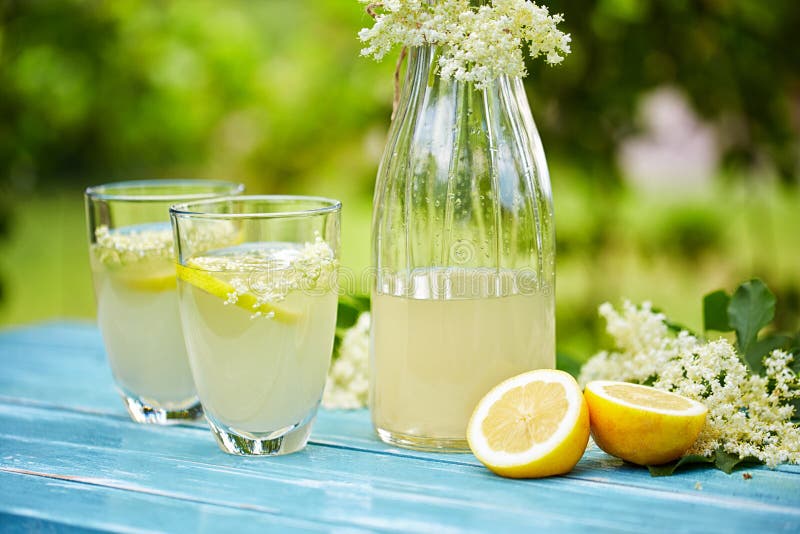 Two glasses and a carafe of elderflower lemonade on table. Two glasses and a carafe of elderflower lemonade on table