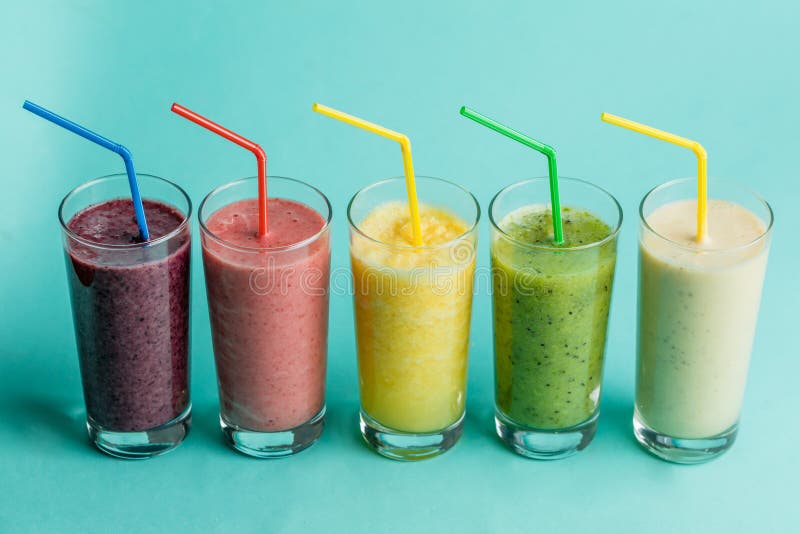 Стекла со свежими очень вкусными smoothie и соломой на изолированной голубой предпосылке стоковые изображения Стекла со свежими очень вкусными smoothie и соломой на изолированной голубой предпосылке стоковые изображения