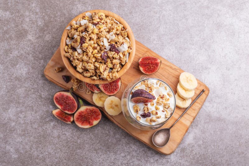 Стекло домодельного granola с югуртом и свежими бананами и смоквами на серой предпосылке шифера стоковые изображения Стекло домодельного granola с югуртом и свежими бананами и смоквами на серой предпосылке шифера стоковые изображения