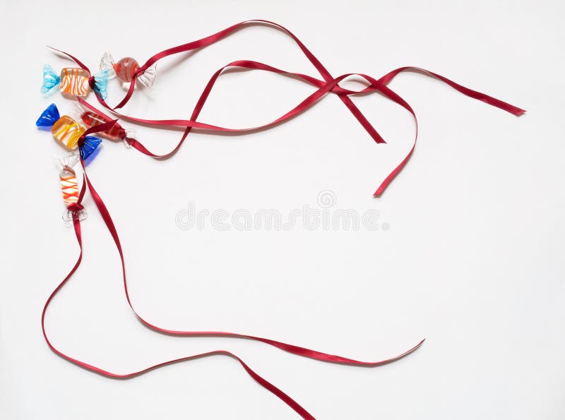 Corner border of glass candies with red satin ribbons isolated on white background as a party invitation. Corner border of glass candies with red satin ribbons isolated on white background as a party invitation.